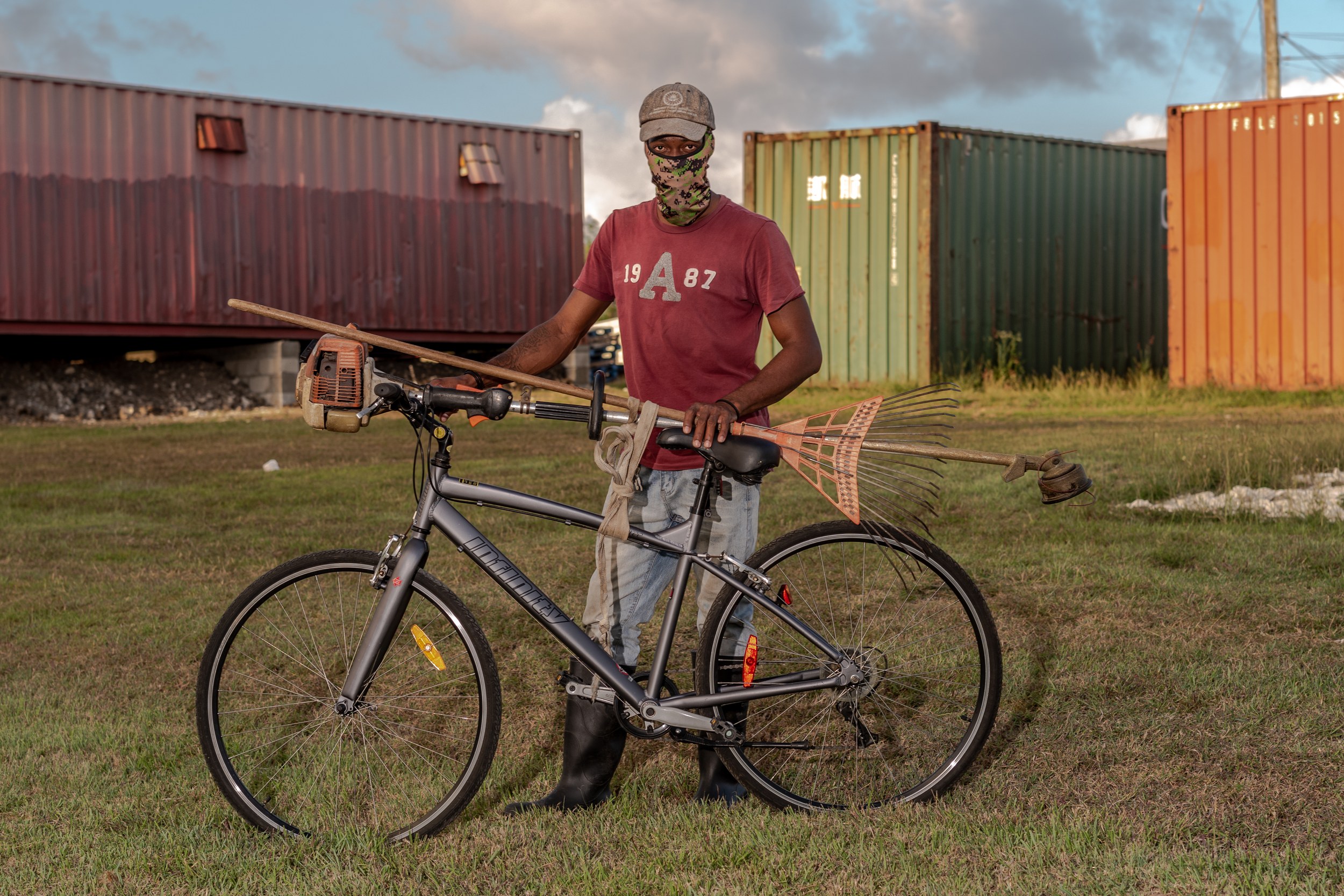 Rashad Knight with a bicycle and landscaping equipment in Barbados