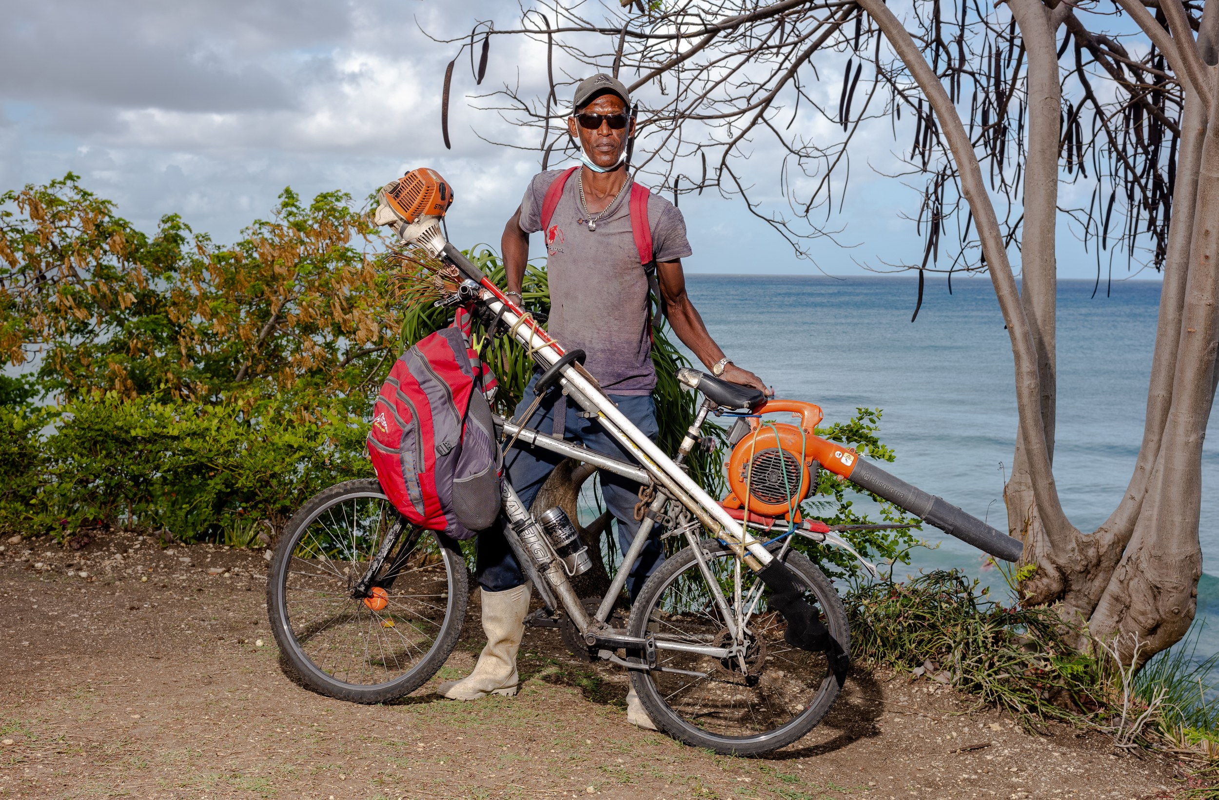 David Phillips with a bicycle and landscaping equipment in Barbados