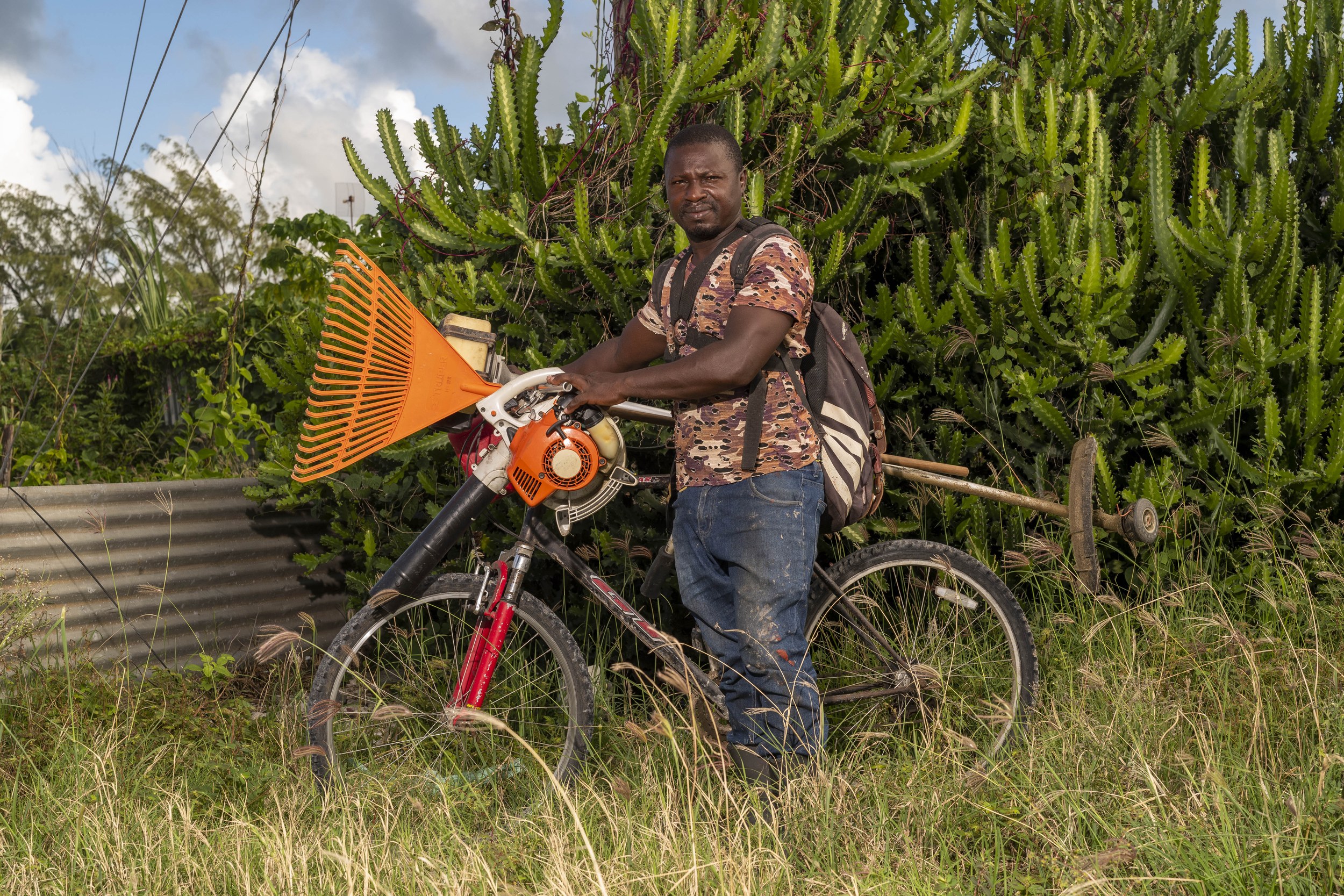 Kevin Davis with a bicycle and landscaping equipment in Barbados