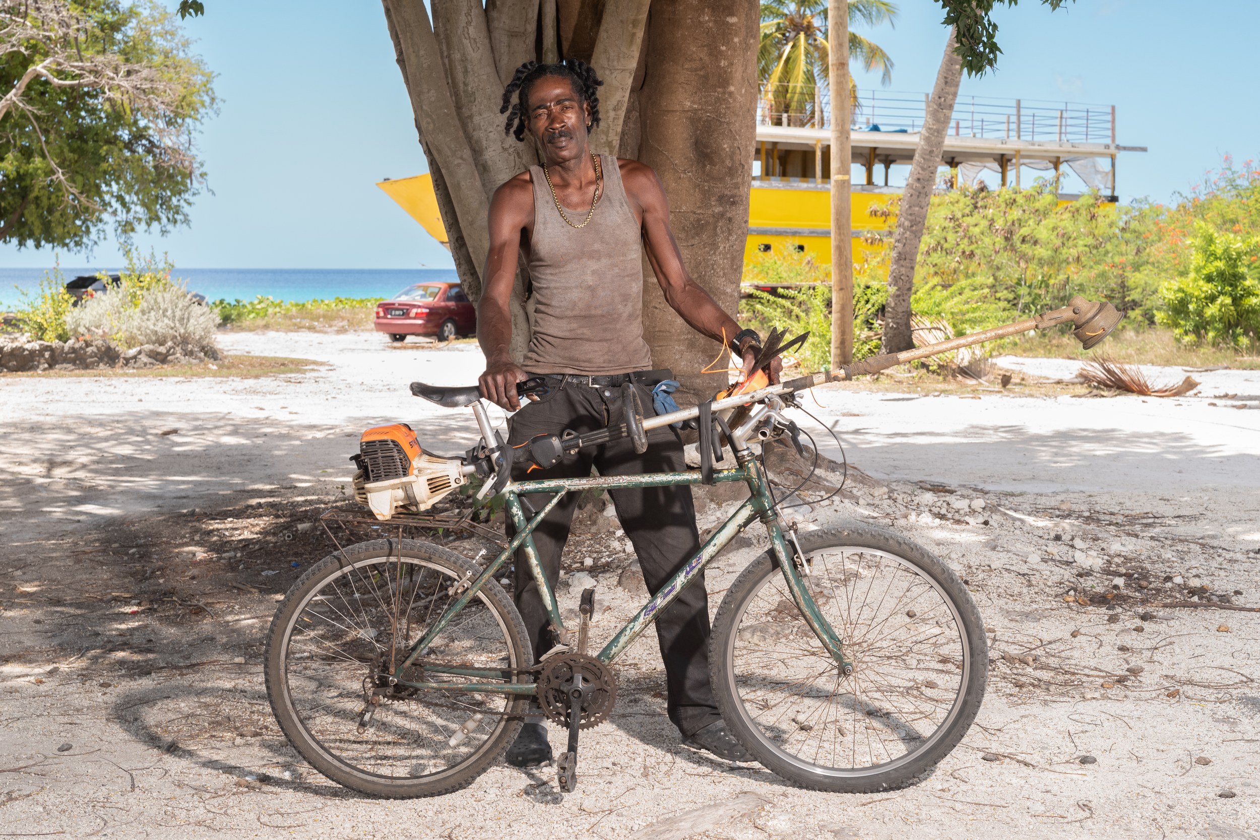Mitchell Dawe with a bicycle and landscaping equipment in Barbados