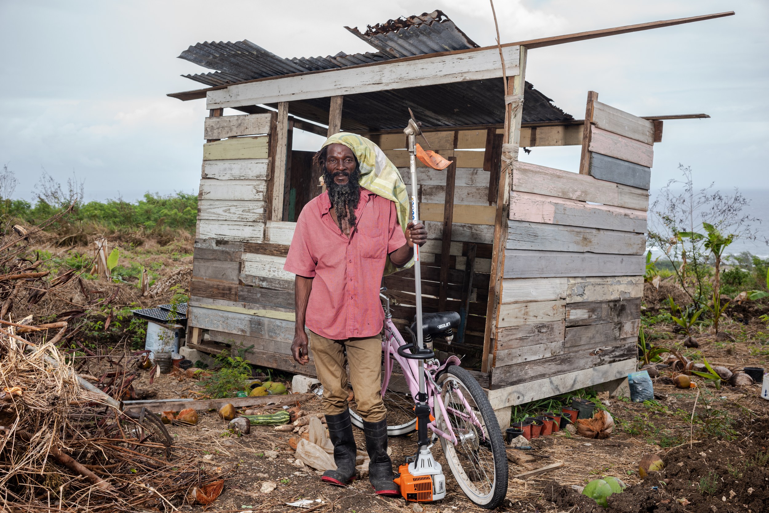 Earl “Early B” Bennett with a bicycle and landscaping equipment in Barbados