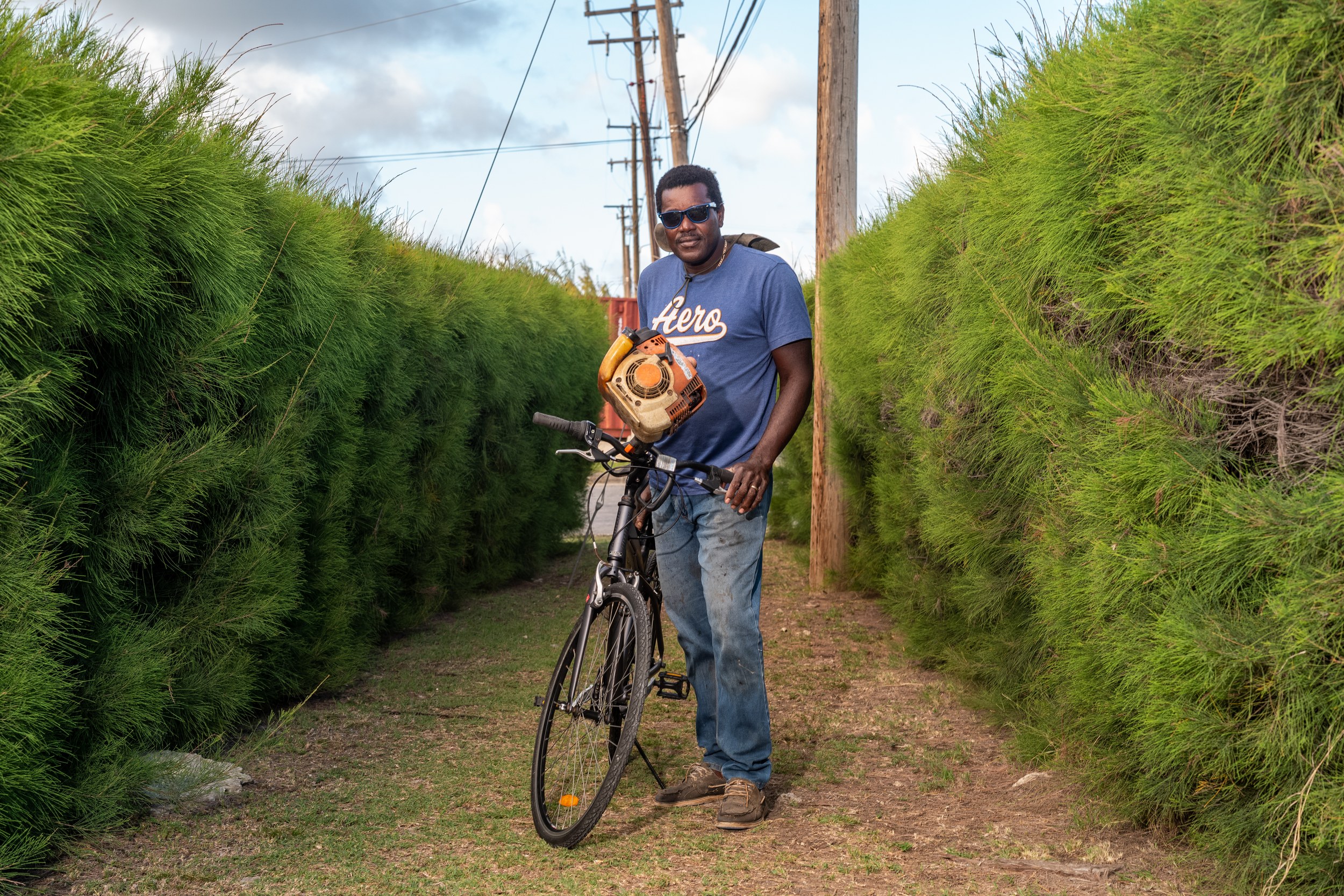 Leroy Benn with a bicycle and landscaping equipment in Barbados