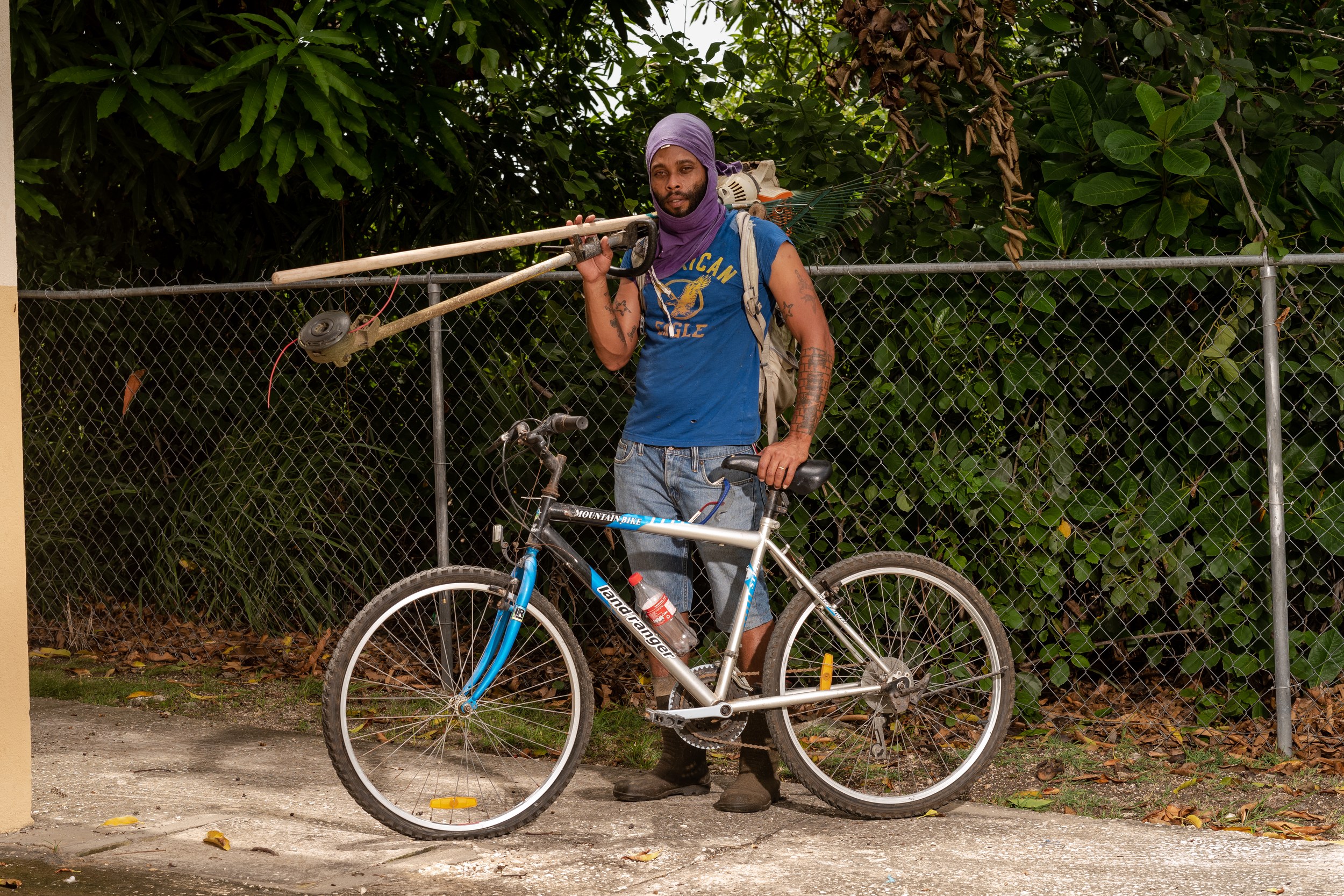 Mario Johnson with a bicycle and landscaping equipment in Barbados
