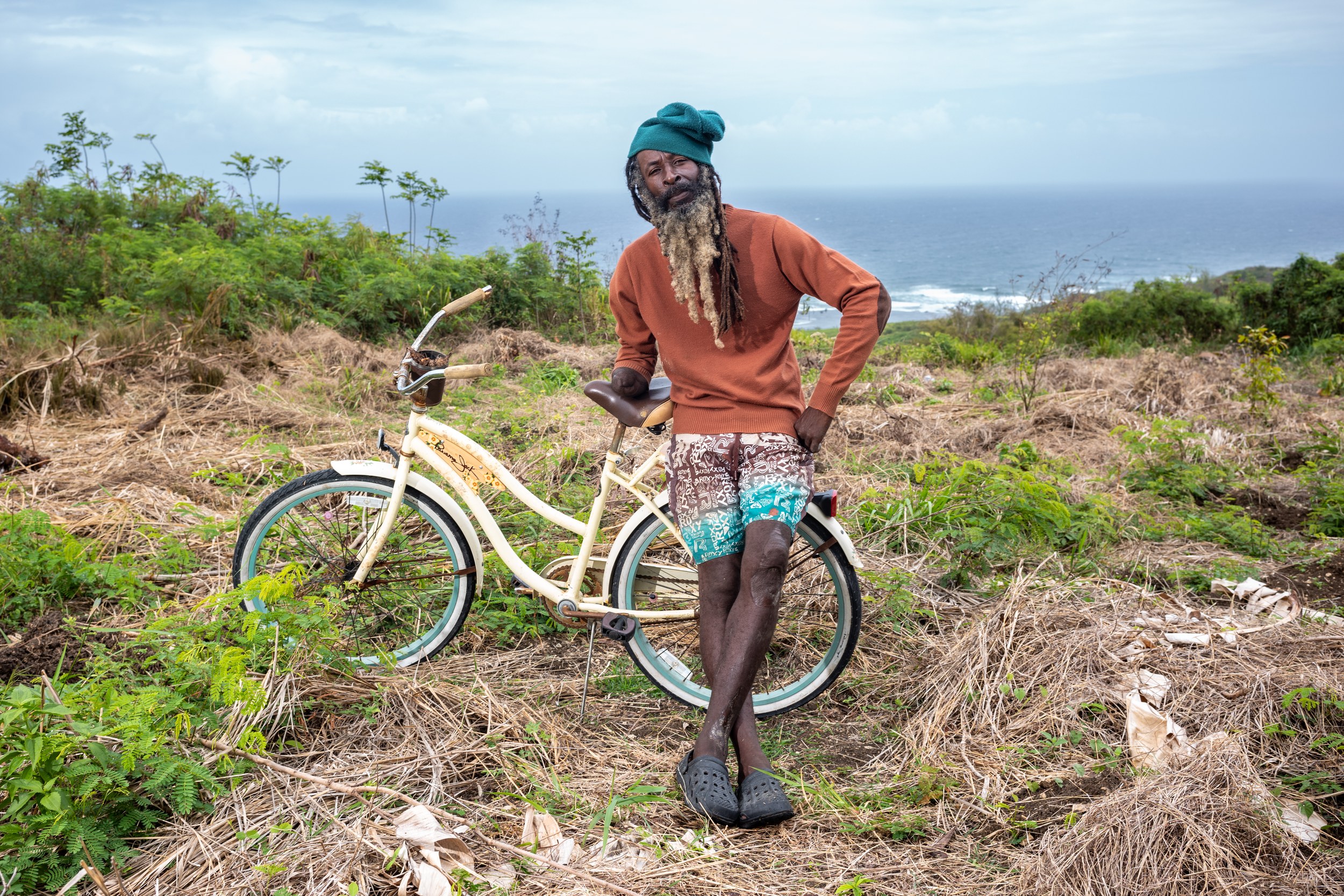 Carlos “Wonie” Simpson with a bicycle and landscaping equipment in Barbados