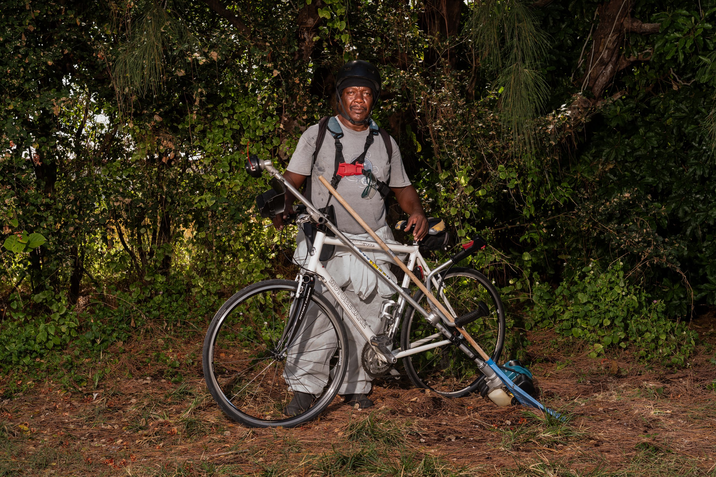 Richard Lashley with a bicycle and landscaping equipment in Barbados