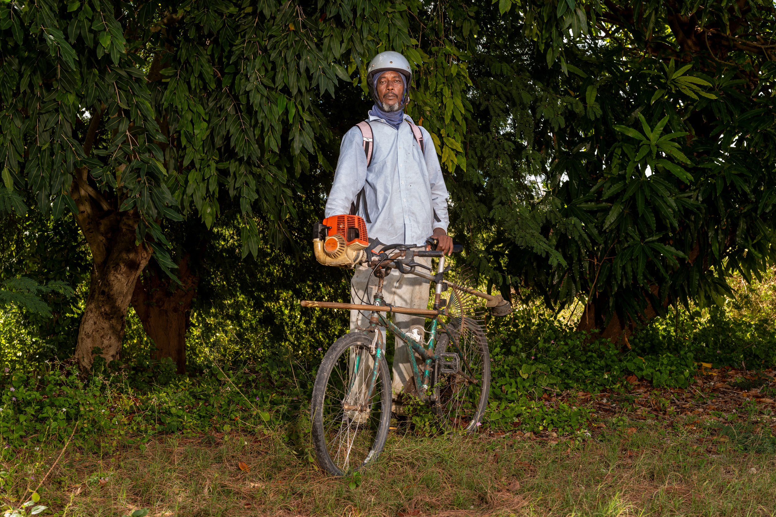 Peter Myers with a bicycle and landscaping equipment in Barbados