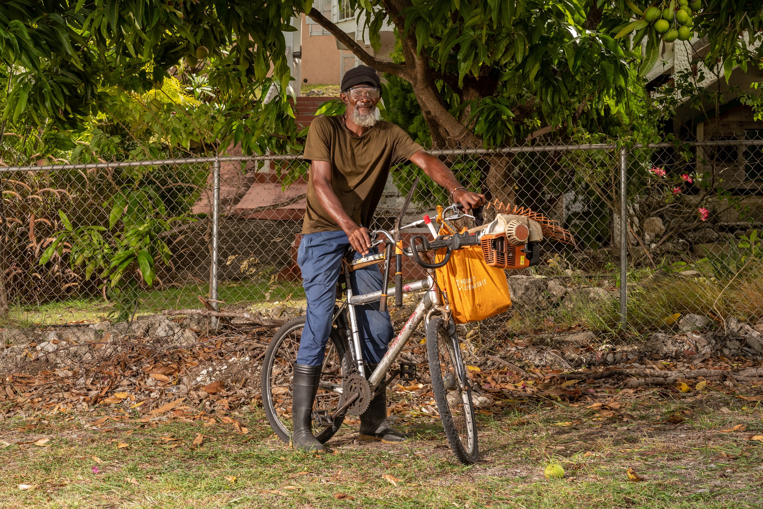 Hunter Toppin with a bicycle and landscaping equipment in Barbados