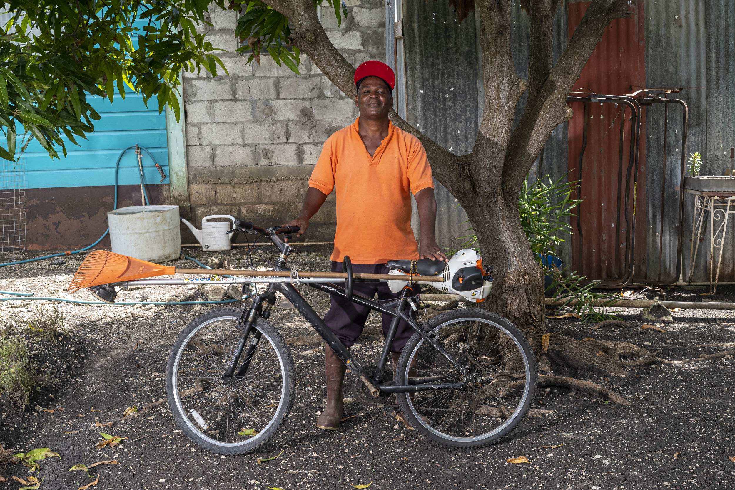 James Cox with a bicycle and landscaping equipment in Barbados