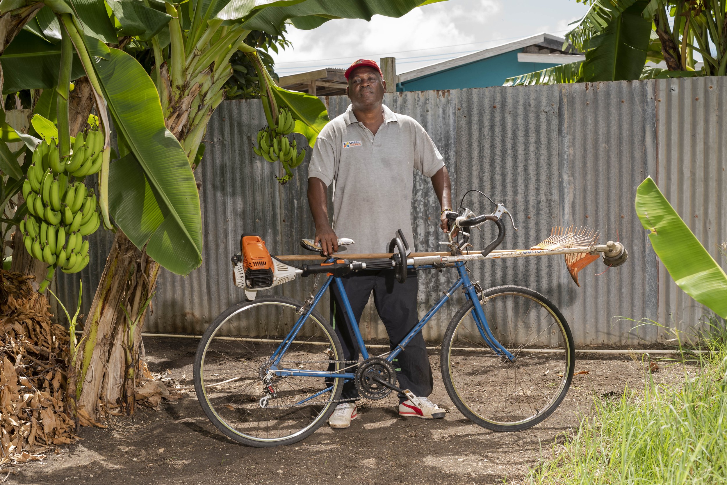 John Cox with a bicycle and landscaping equipment in Barbados