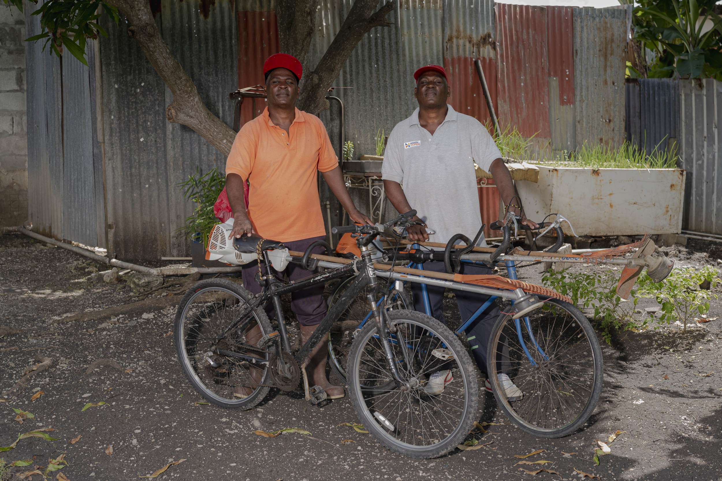 John and James Cox with a bicycle and landscaping equipment in Barbados