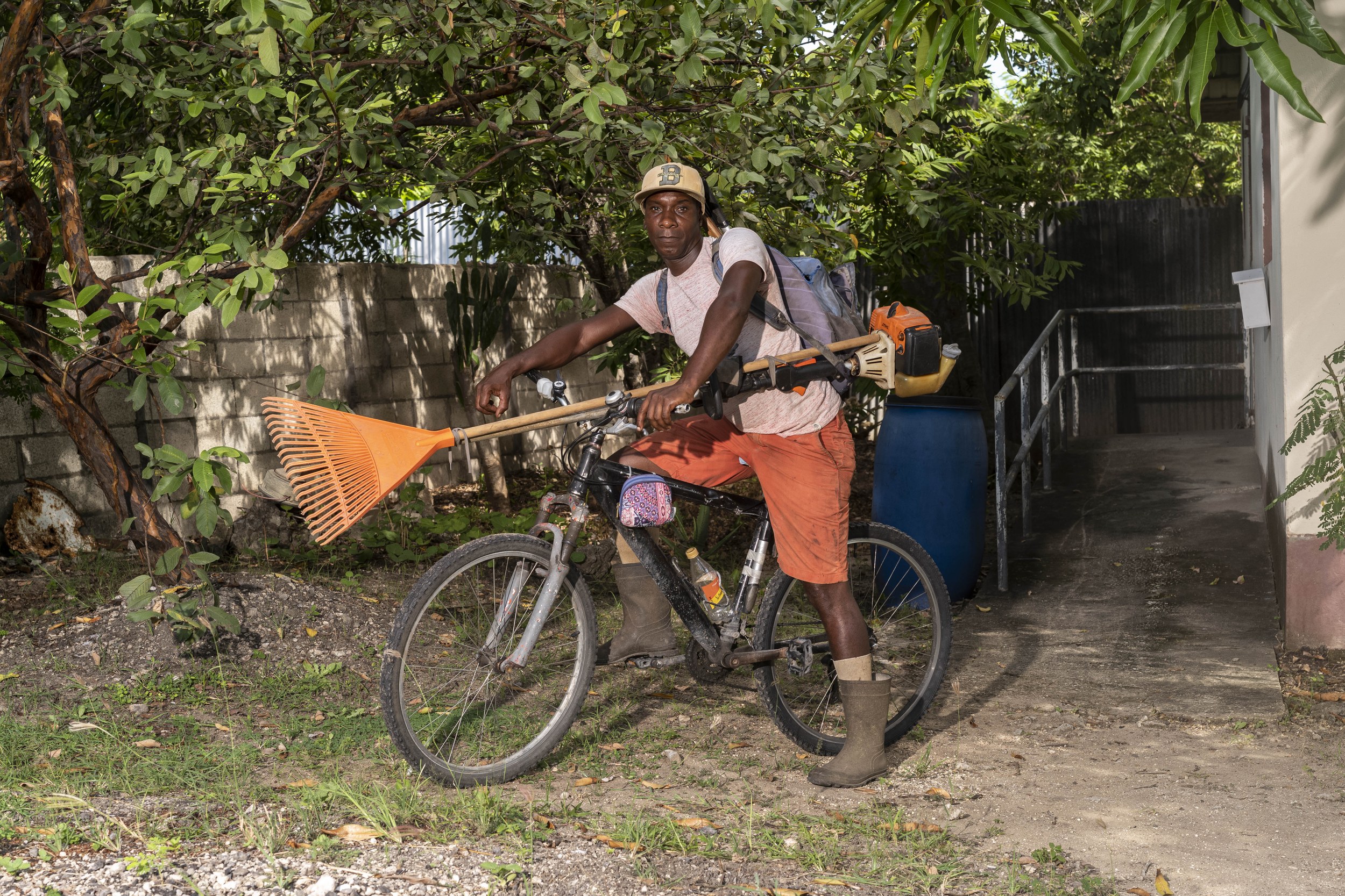 Maurice Ashby with a bicycle and landscaping equipment in Barbados