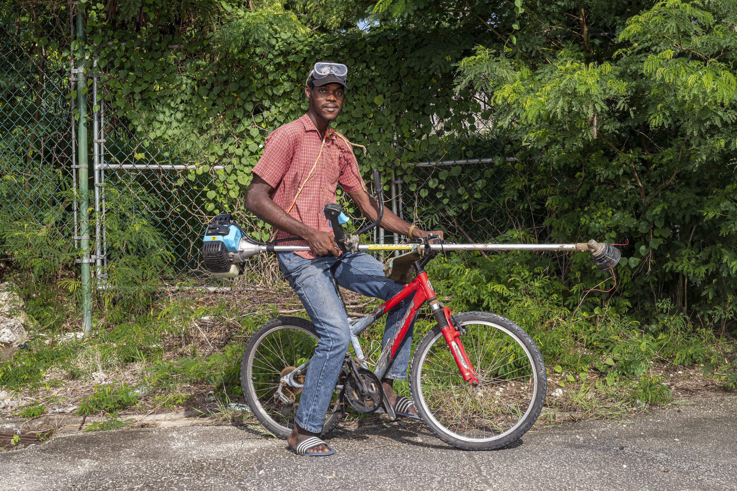 Rikeino Maynard with a bicycle and landscaping equipment in Barbados