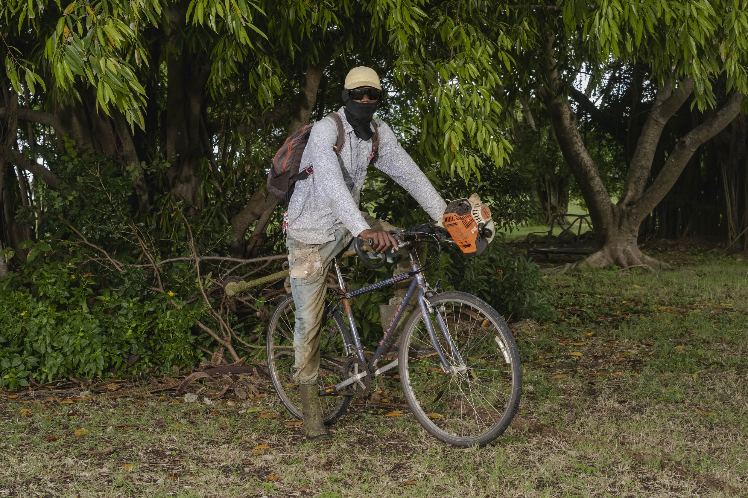 Ken Roberts with a bicycle and landscaping equipment in Barbados