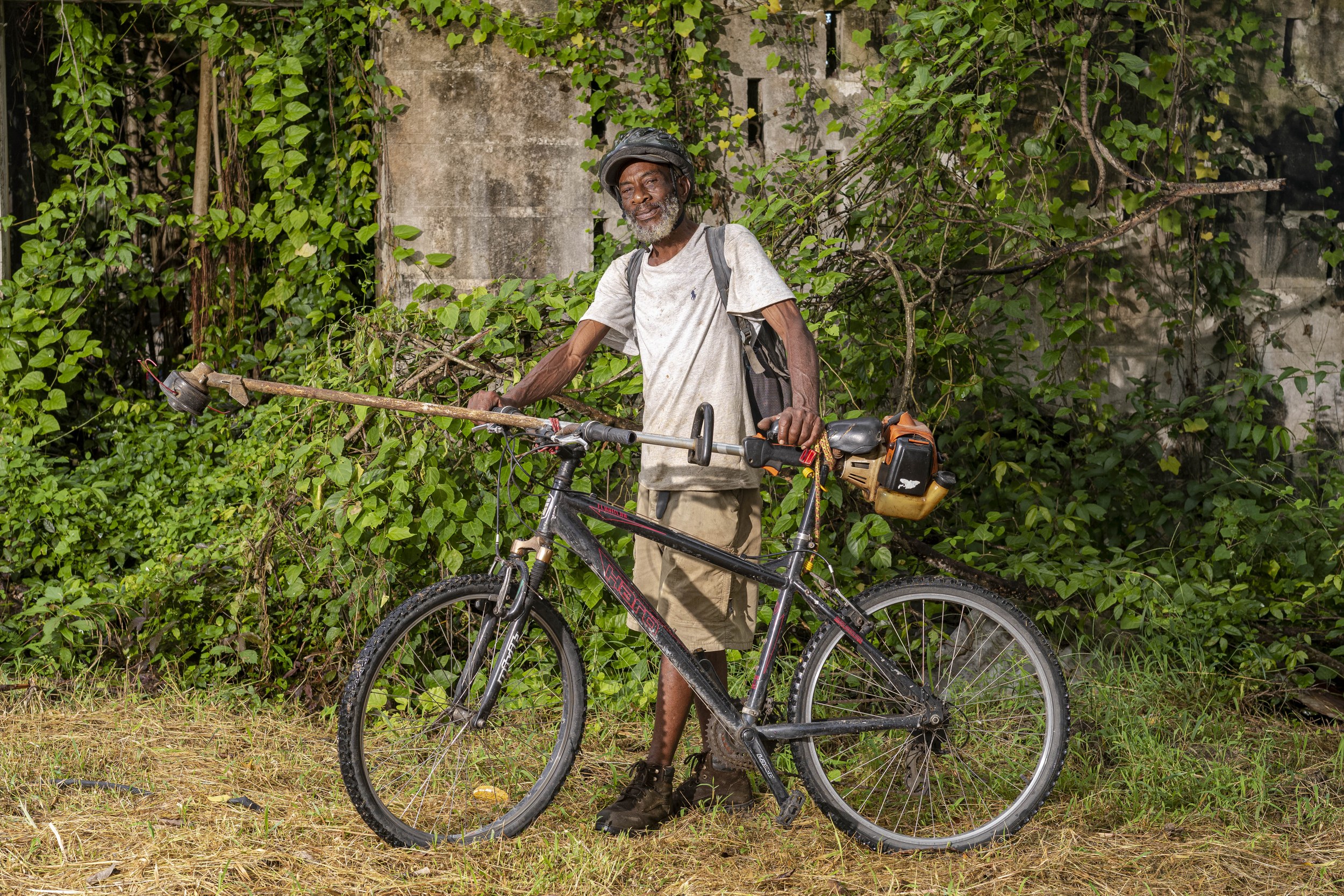 Hassan Ali with a bicycle and landscaping equipment in Barbados