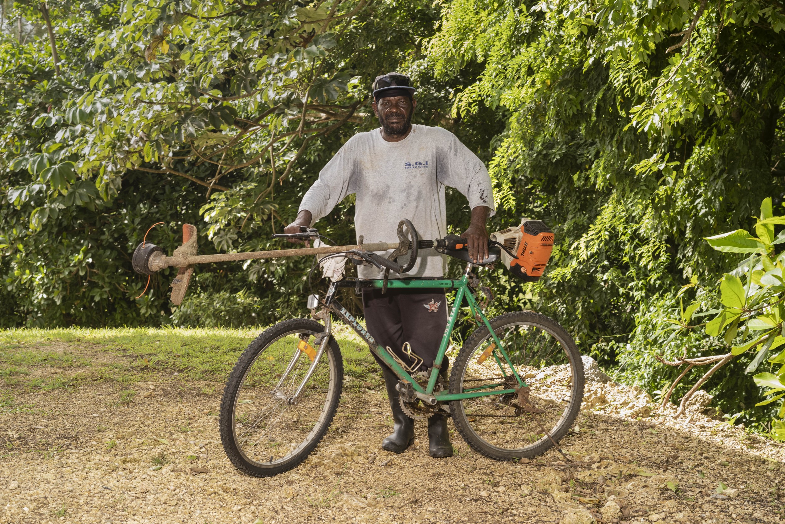 George Alexander with a bicycle and landscaping equipment in Barbados