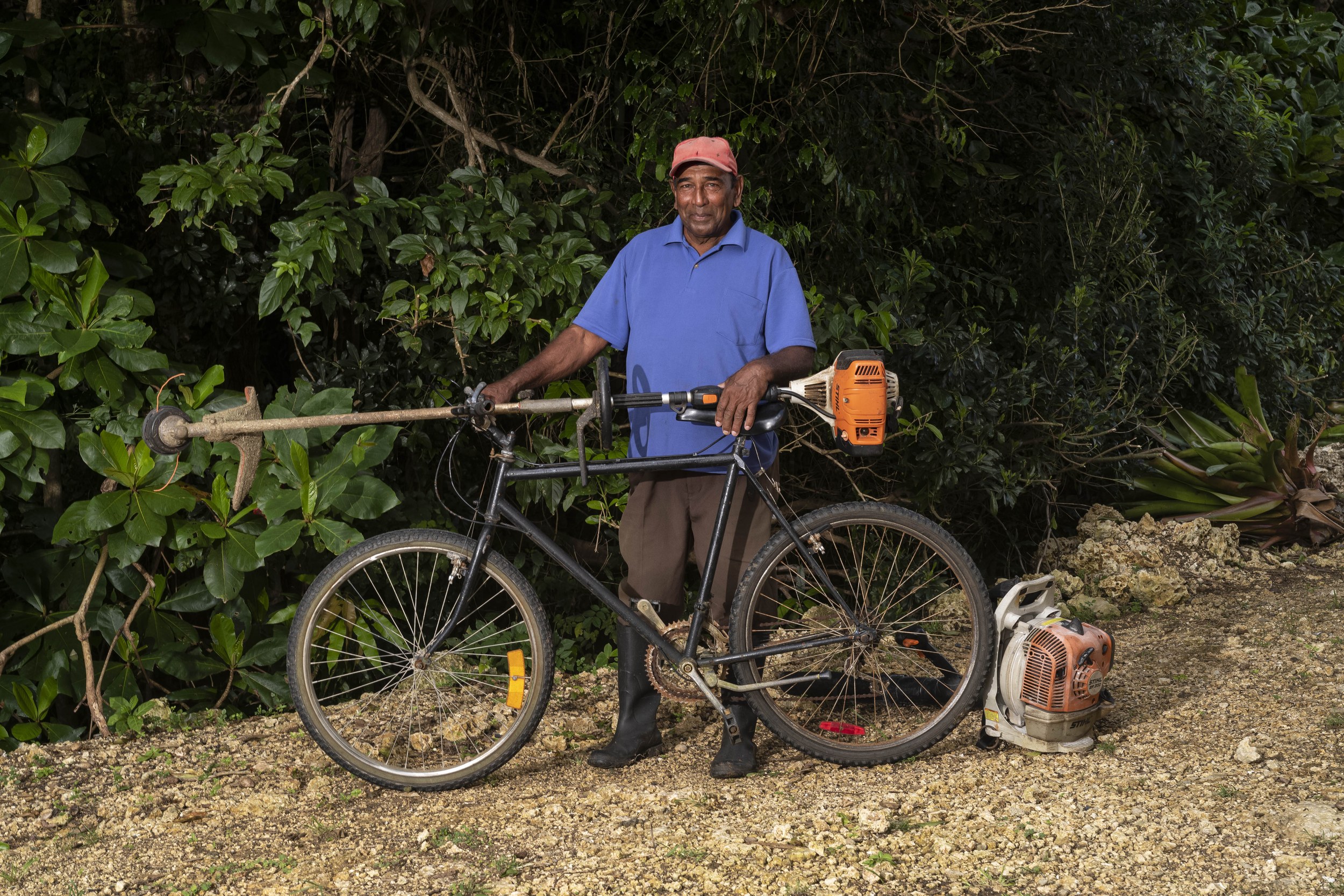 Narainjan Dasasan with a bicycle and landscaping equipment in Barbados