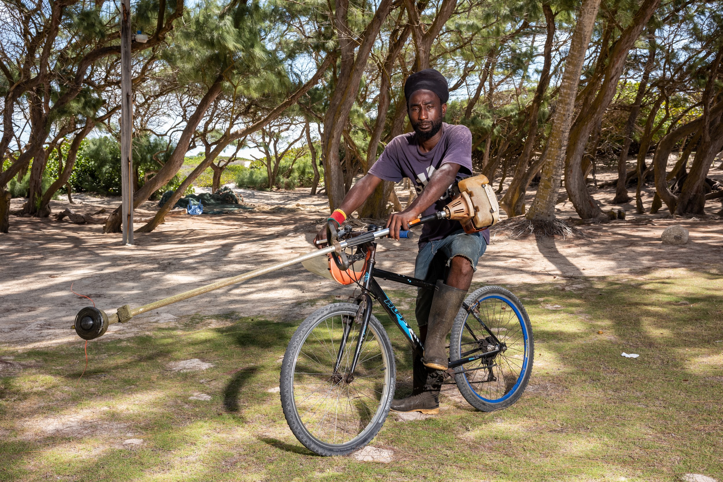 Ryan Pilgrim with a bicycle and landscaping equipment in Barbados