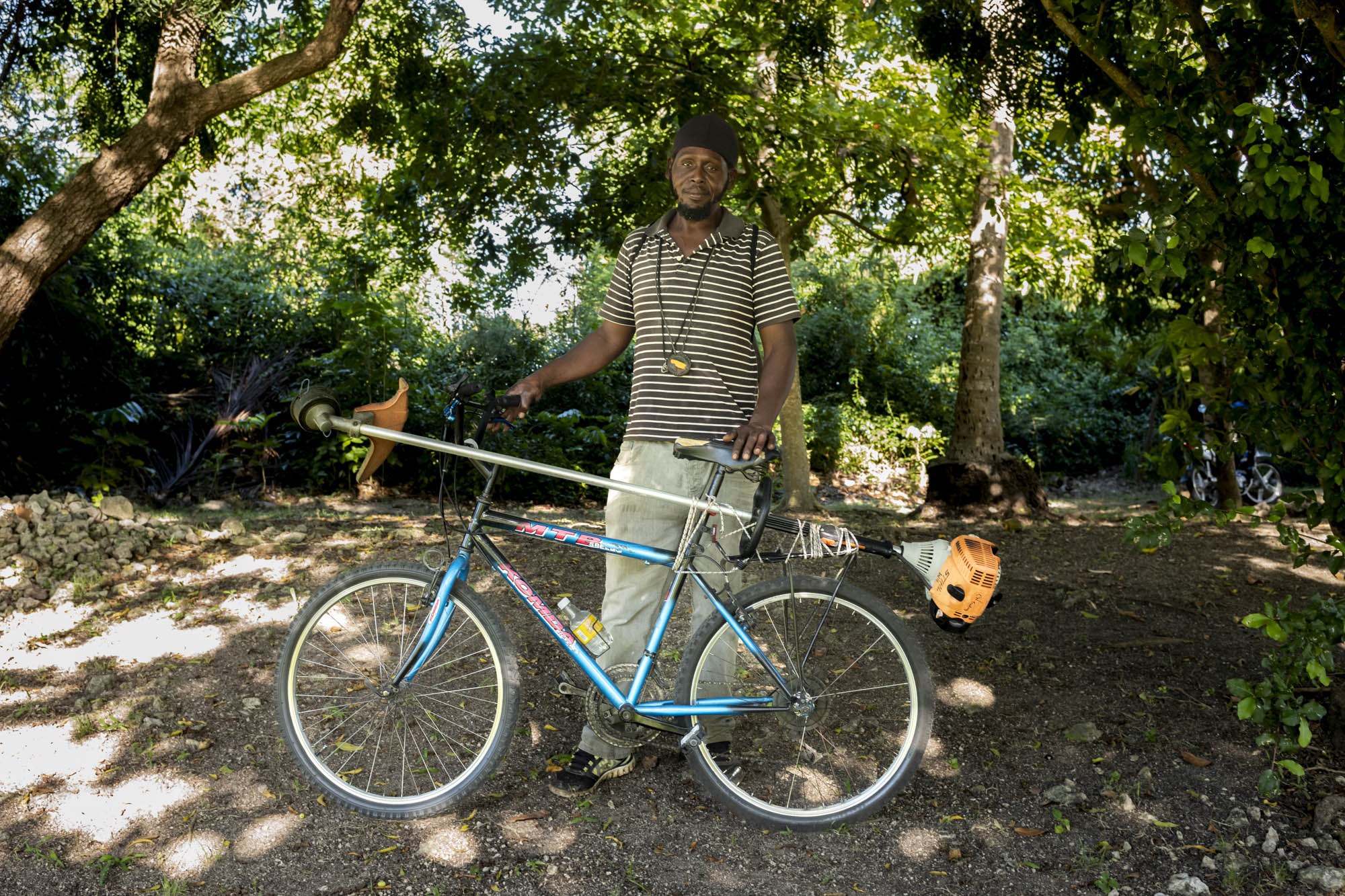 Anderson Puckerin with a bicycle and landscaping equipment in Barbados