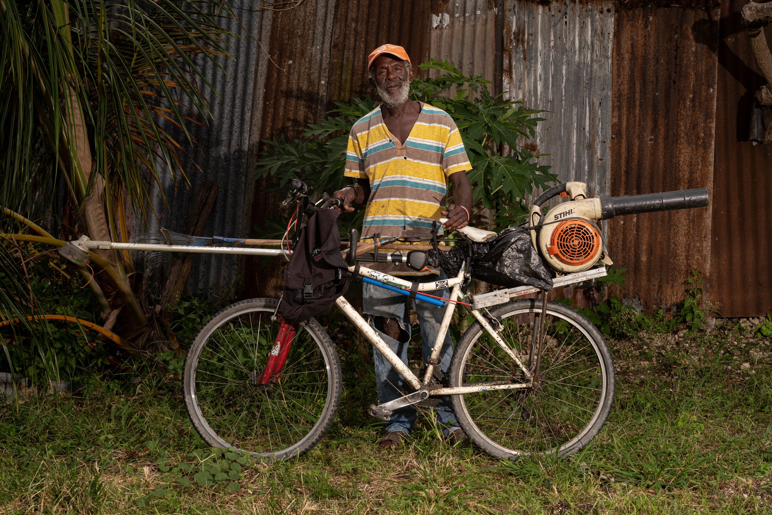 George Ferdinand with a bicycle and landscaping equipment in Barbados