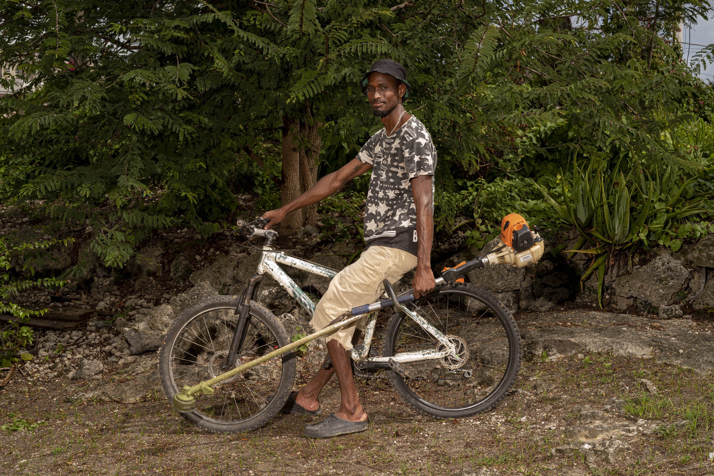 Shaquan Harding with a bicycle and landscaping equipment in Barbados