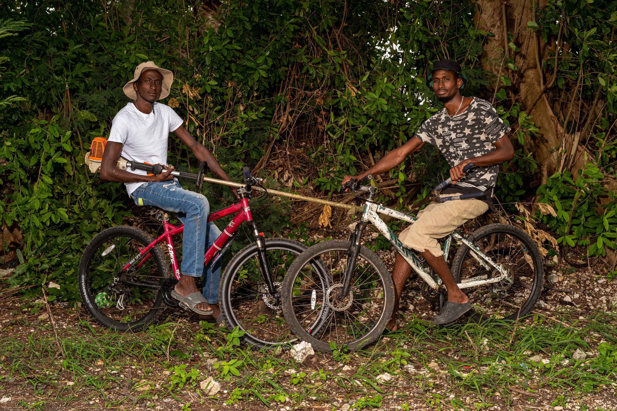 Brothers Shaquille Dawn and Shaquan Harding with a bicycle and landscaping equipment in Barbados