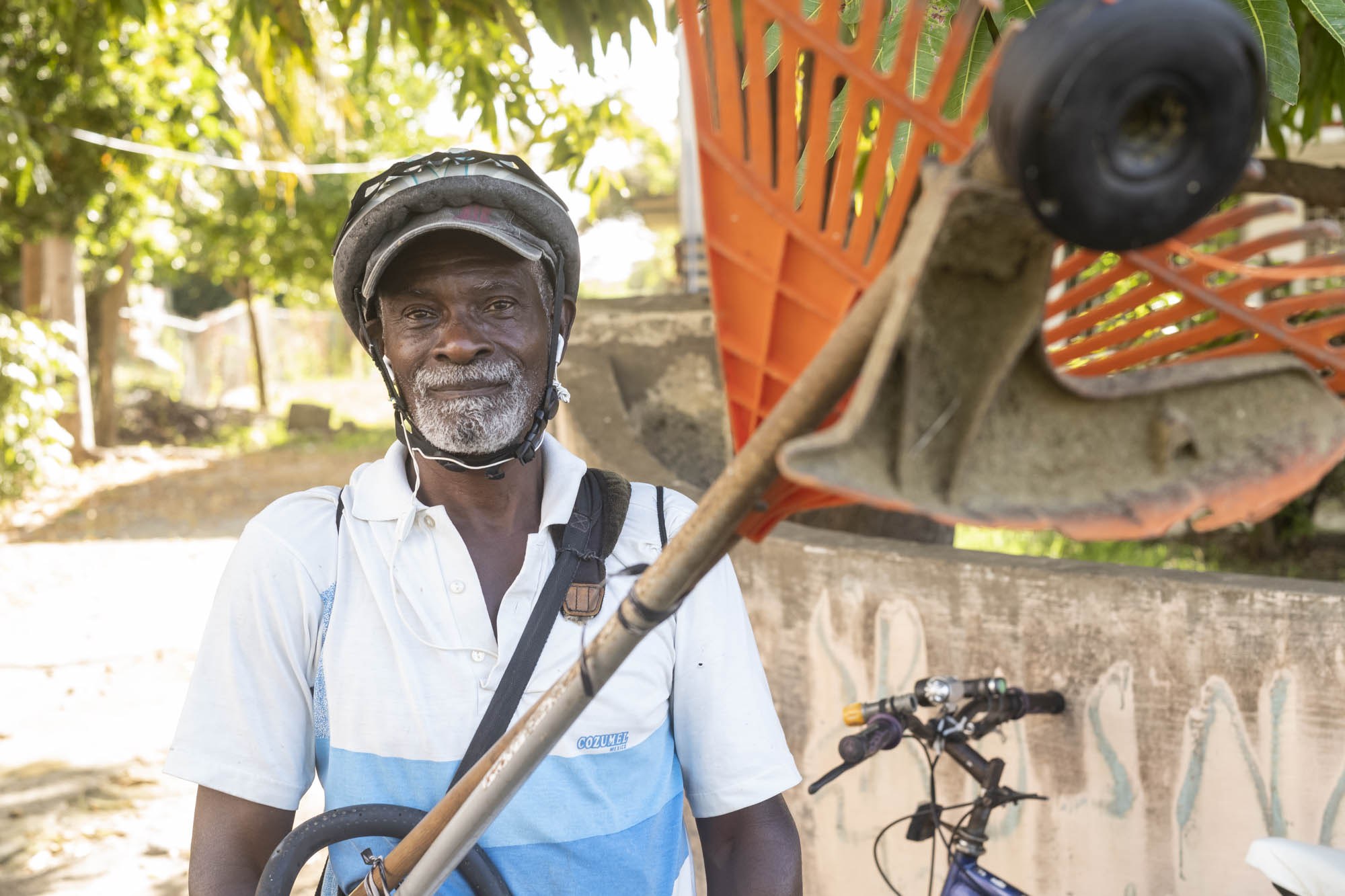 Ronald Ashby with a bicycle and landscaping equipment in Barbados