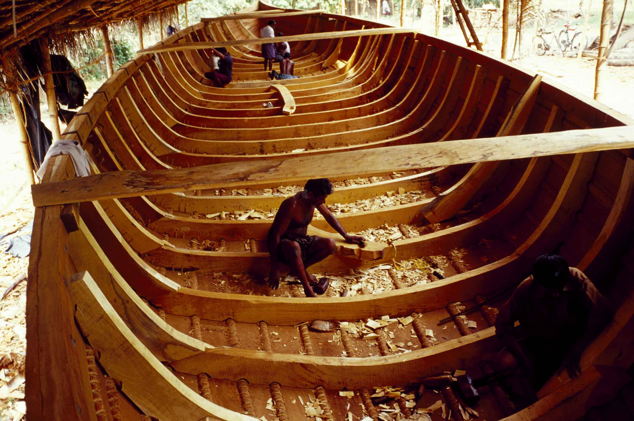 Boatbuilders in Kerala State carve the wooden hull of a houseboat, 2005