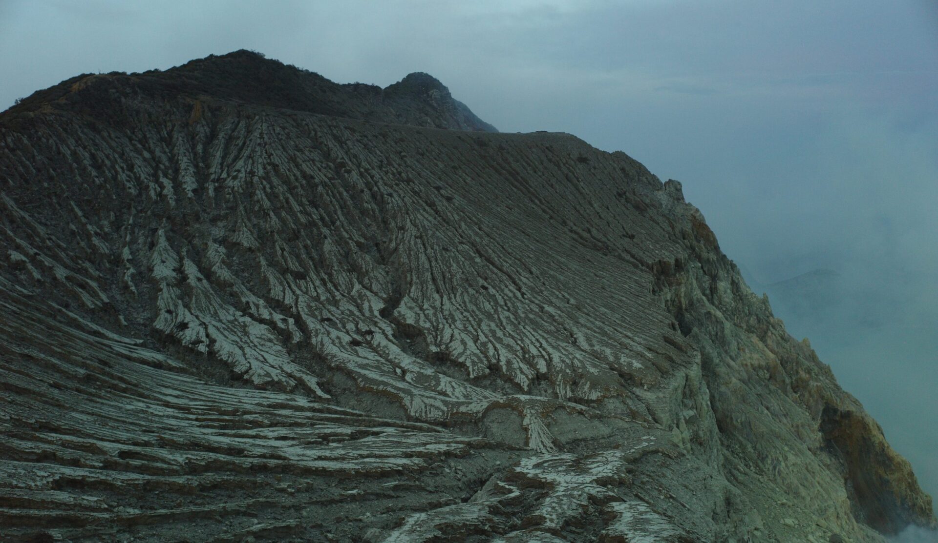 The scarred walls of Kawah Ijen's crater lit by moonlight
